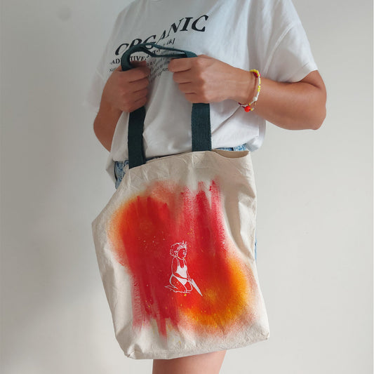 a girl is holding a hand painted tote bag